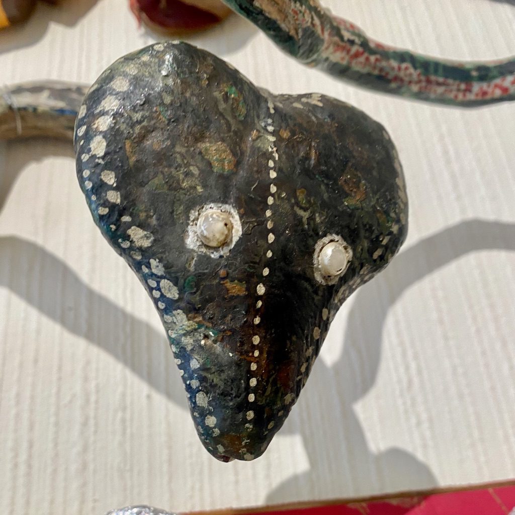 An anonymous artwork from Zoooo! at the Gallery of Everything. A snake with a heart shaped head and pearls for eyes regards you with a soft gaze.