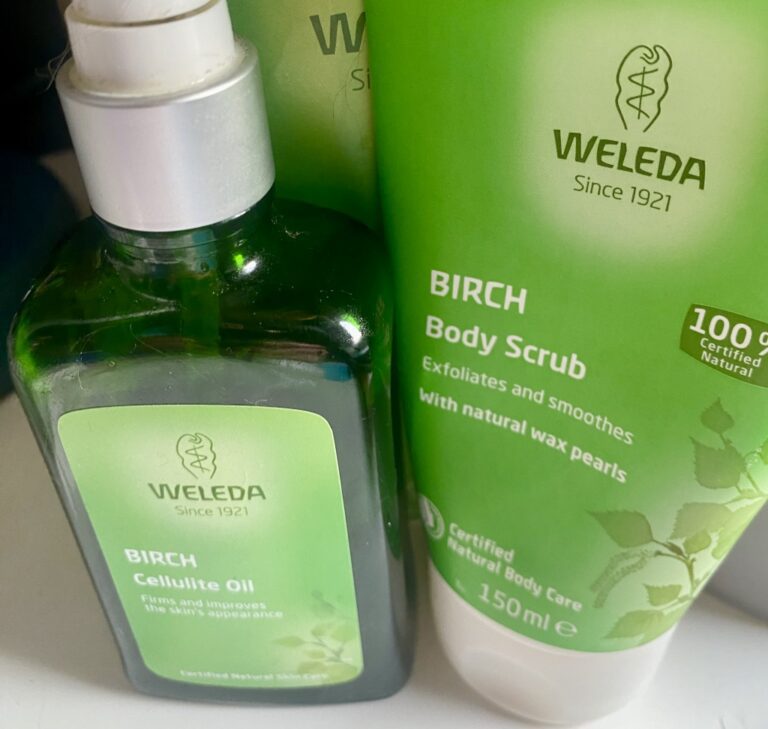 WELEDA BIRCH Body Scrub and Cellulite Oil close up. Products packaged in bright green livery. both are well used. The tube of Body Scrub is squeezed and depleted, the bottle of oil is half-empty