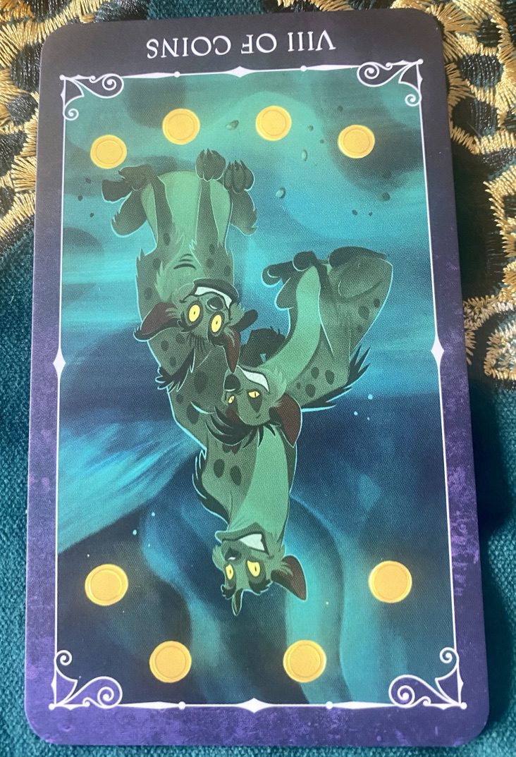 Disney Villains tarot card showing Hyaenas reversed eight coins float in the air around them and the coins are the same golden yellow as the hyaenas' eyes