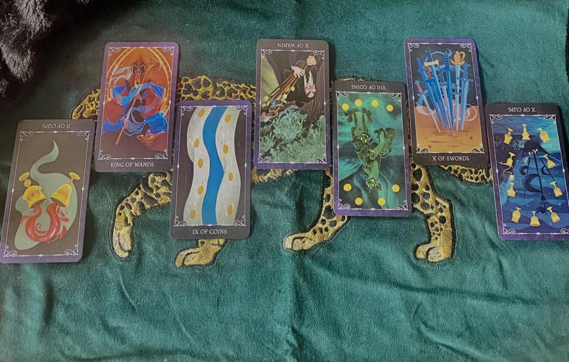 Disney Villain tarot cards laid out on a green velvet cloth over an embroidered leopard