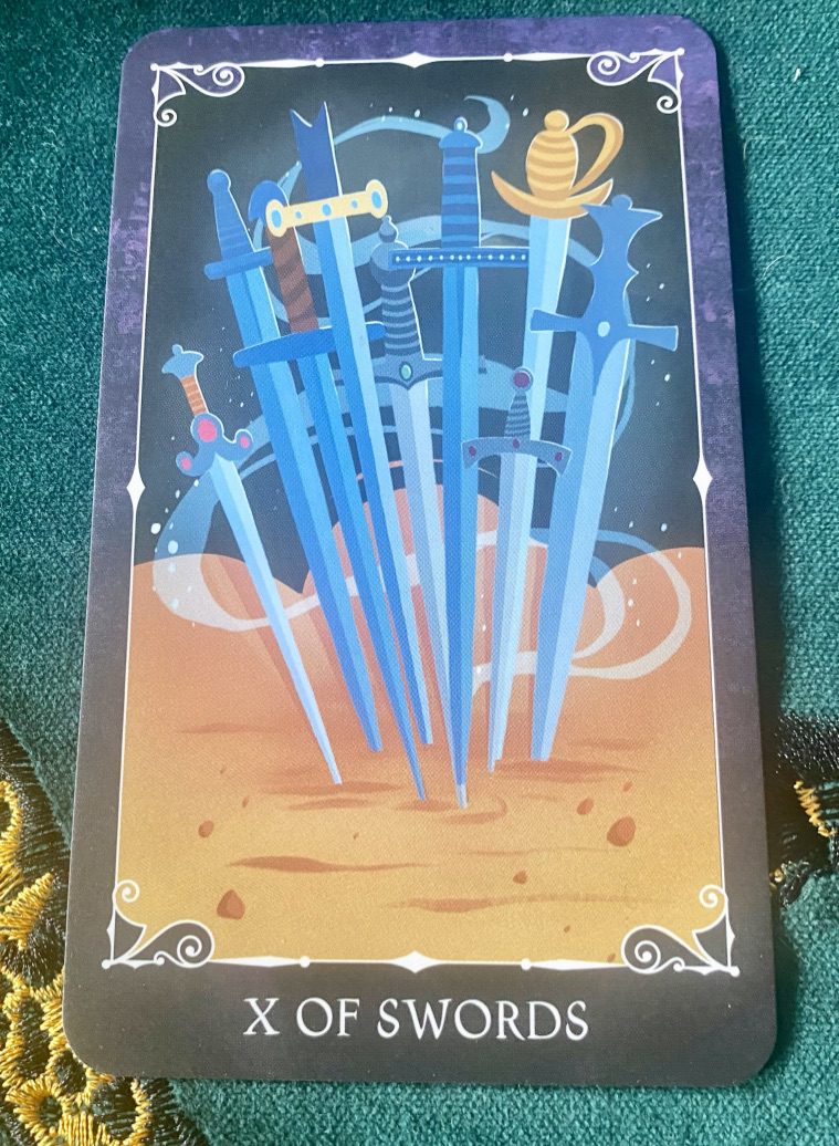 Disney Villains tarot card showing ten blue swords plunged into what looks like golden sand