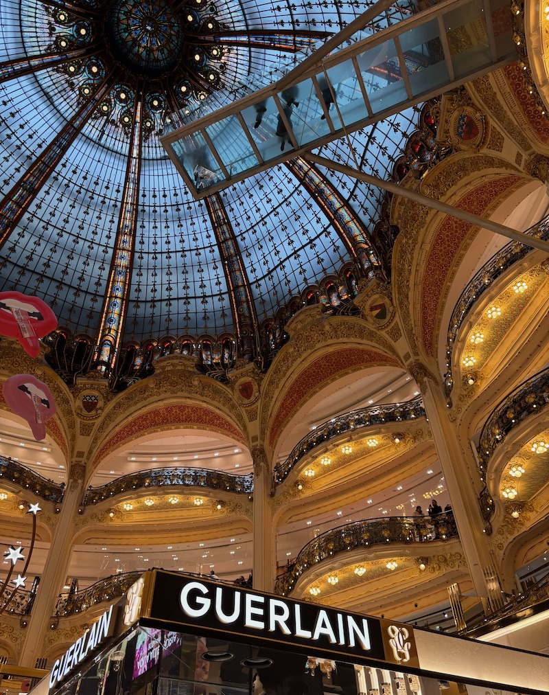 Dome of Galeries Lafayette at dusk with 'GUERLAIN' in the foreground